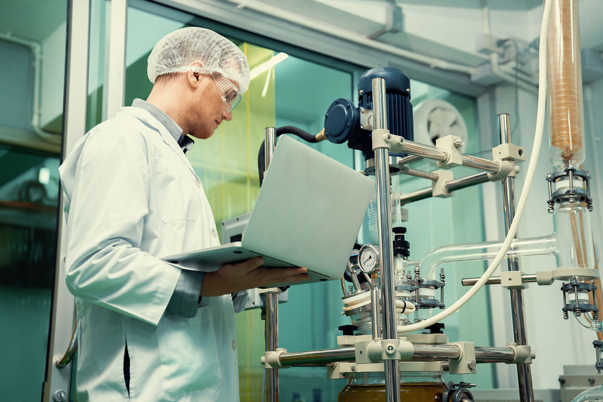 Person holding laptop and monitors CBD oil machine